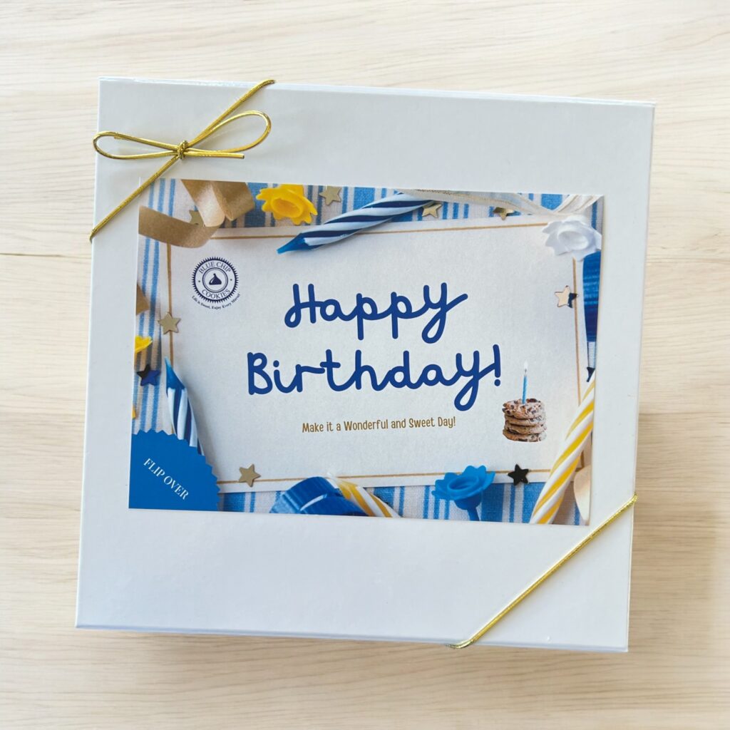 Birthday card with gold ribbon on wooden surface