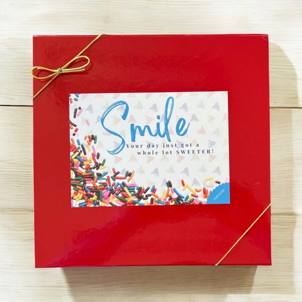 Red gift box with 'Smile' card and golden ribbon