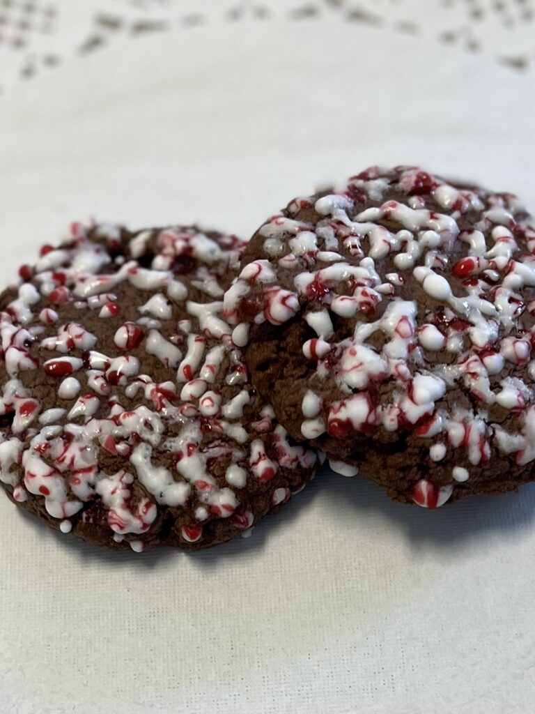 Chocolate cookies topped with white icing and candy cane bits