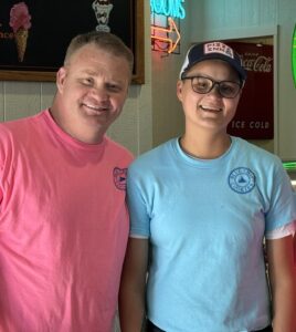 Three people smiling in a diner with neon signs