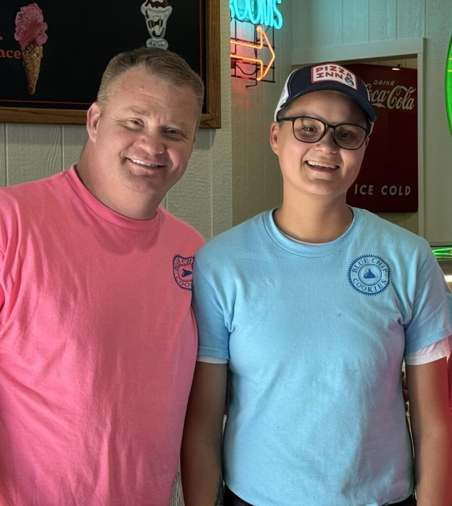 Three people smiling in a diner with neon signs