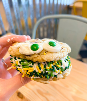 Hand holding festive sprinkled cookie sandwich